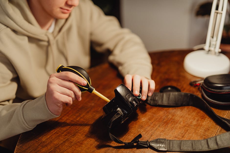 Personne utilisant un soufflet pour nettoyer un appareil électronique